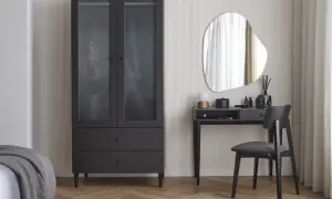 Eleganckie biurko w sypialni z lustrem i czarnym krzesłem obok szafy.