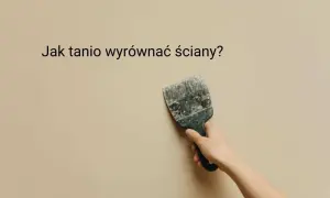 Ręka trzyma szpachelkę przy beżowej ścianie, sugerując, jak tanio wyrównać ściany.