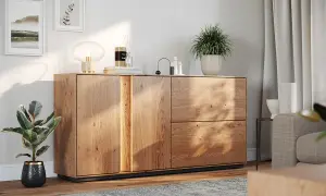 Drewniana komoda z dekoracjami: lampa, świeca, rośliny. Świetny pomysł na dekoracje komody w nowoczesnym salonie.
