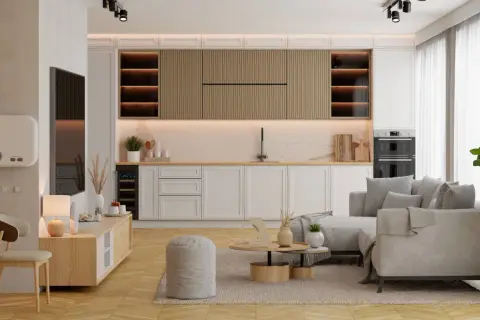 Nowoczesny salon z aneksem kuchennym. Jasne meble, wygodna sofa i funkcjonalna zabudowa kuchenna tworzą przytulną przestrzeń.