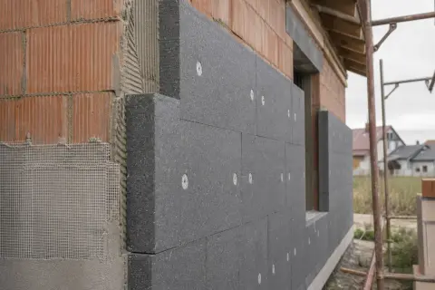 Szary styropian grafitowy o grubości 20 cm, mocowany do ceglanego muru 40 cm, tworzy warstwę izolacyjną.