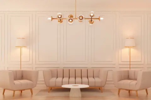 Elegancki salon w stylu glamour z beżową kanapą, dwoma fotelami, okrągłym stolikiem i złotą lampą.