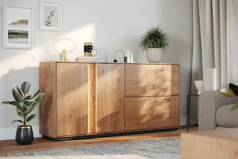 Drewniana komoda z dekoracjami: lampa, świeca, rośliny. Świetny pomysł na dekoracje komody w nowoczesnym salonie.