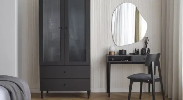 Eleganckie biurko w sypialni z lustrem i czarnym krzesłem obok szafy.
