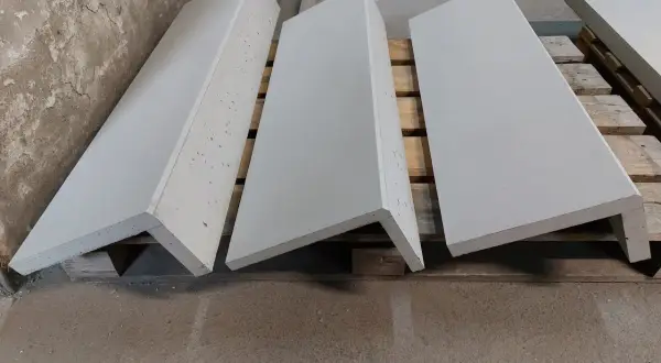 Gotowe elementy na wykładzinę na schody betonowe. Trzy szare stopnie leżą na drewnianych paletach.