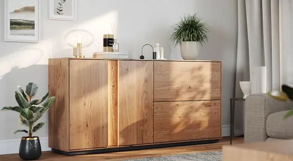 Drewniana komoda z dekoracjami: lampa, świeca, rośliny. Świetny pomysł na dekoracje komody w nowoczesnym salonie.