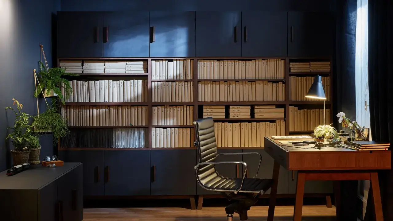 Elegancka biblioteczka z segregatorami i dokumentami pokazuje, jak przechowywać dokumenty w domu. Wygodne biurko i stylowe krzesło tworzą idealne miejsce do pracy.
