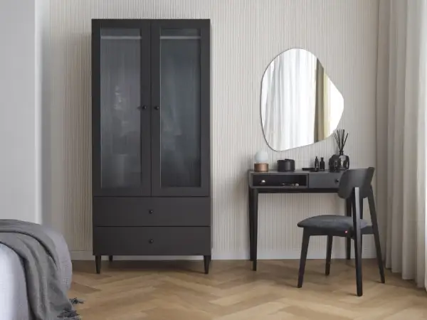 Eleganckie biurko w sypialni z lustrem i czarnym krzesłem obok szafy.
